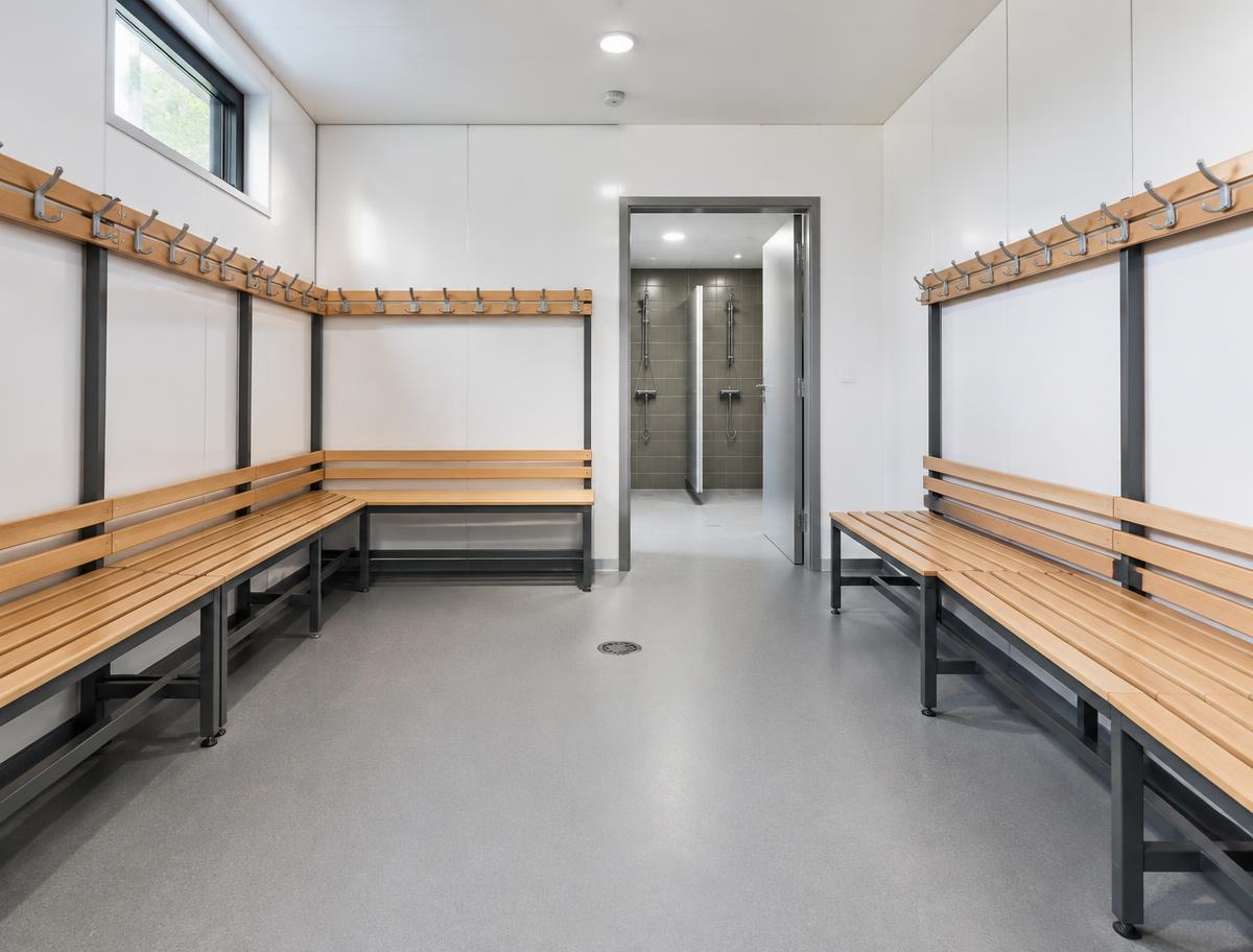 Modular changing room with slatted benches, coat hooks and doorway to showers